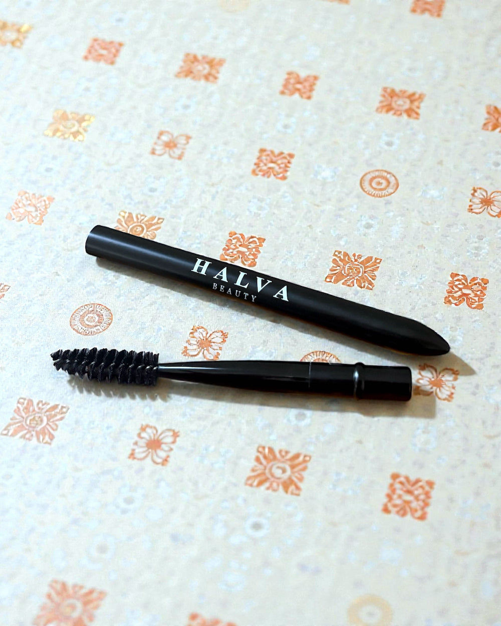 Halva beauty spoolie showing the spoolie brush and cap on a patterned surface