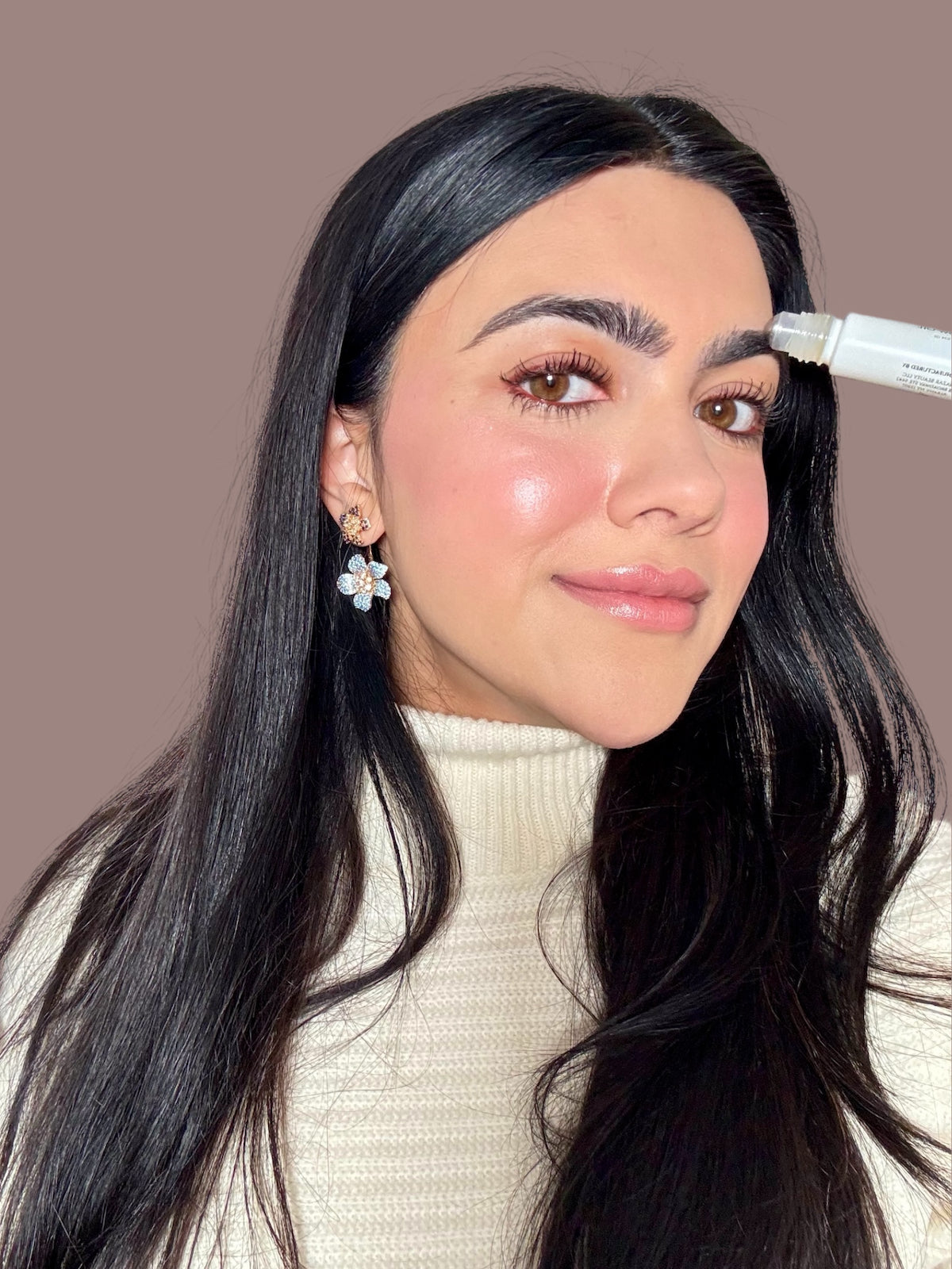 halva beauty founder applying halva beauty brow oil with rollerball for natural brow growth
