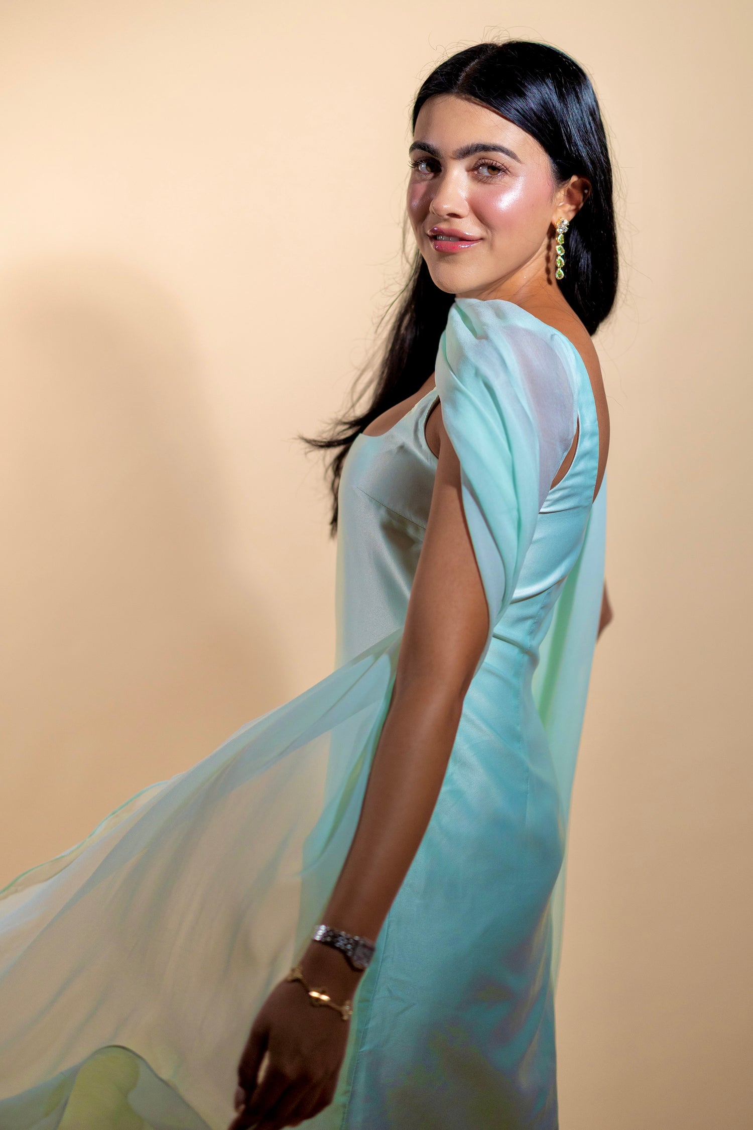 halva beauty founder kiren ajrawat wearing a flowing mint indian dress with natural glowing makeup and softly defined brows against a warm neutral backdrop