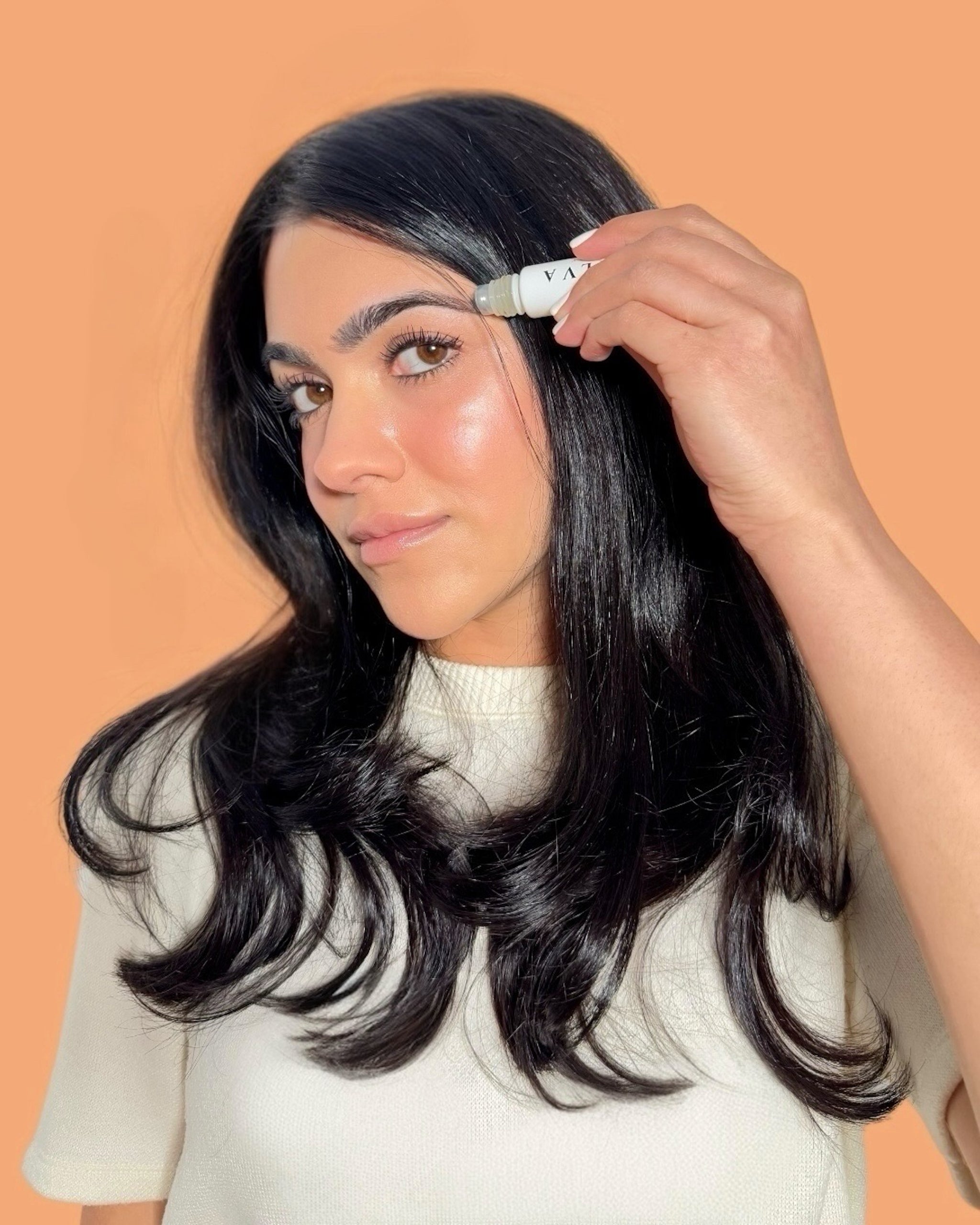 halva beauty founder applying nourishing brow oil rollerball to brows