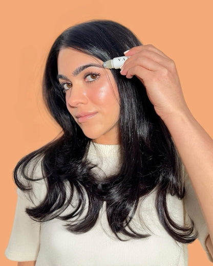 halva beauty founder applying nourishing brow oil rollerball to brows