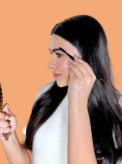 halva beauty founder looking in the mirror and brushing brows using the halva beauty spoolie