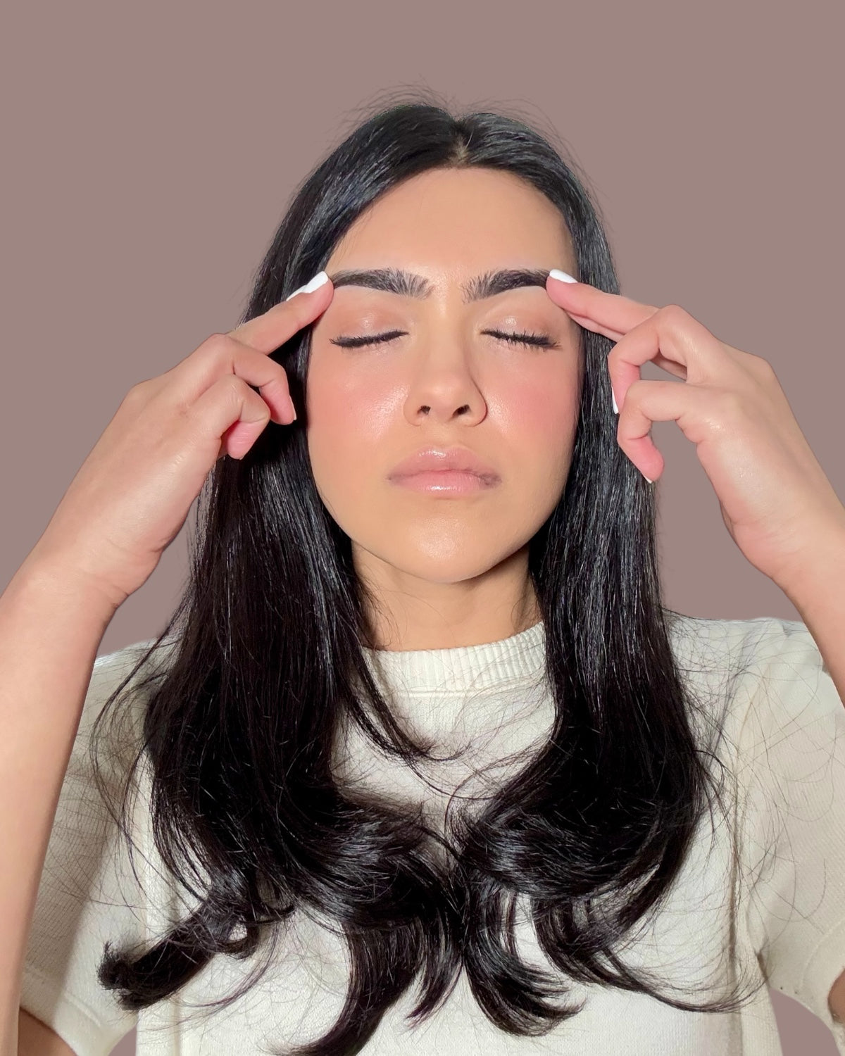 gently massaging brow oil into eyebrows to support natural growth and thickness
