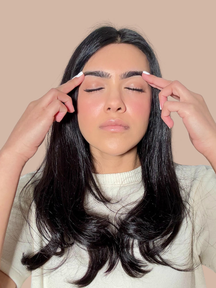 step 2: massaging halva beauty nourishing brow oil into brows using fingertips
